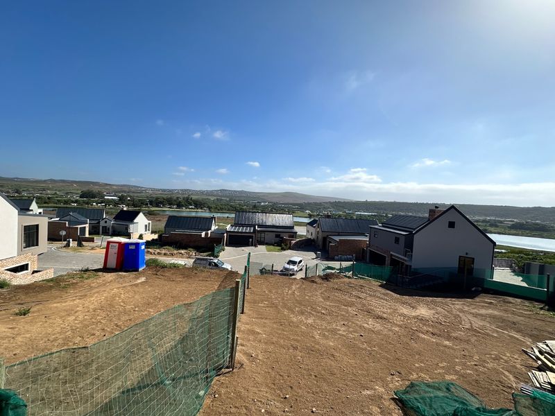 An elevated view overlooking a residential development site with surrounding landscape and water features in the distance.