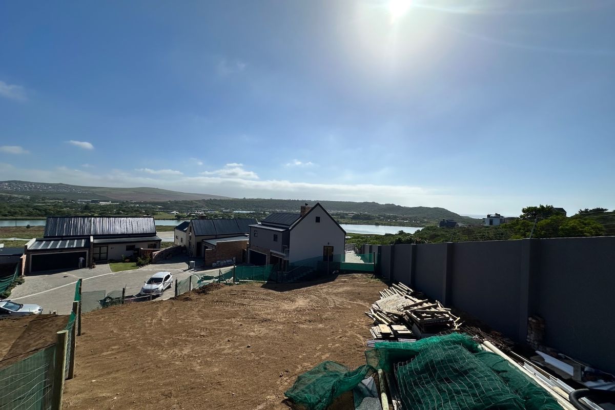 An elevated view of a vacant residential plot under development, featuring perimeter walling and surrounding neighborhood views.