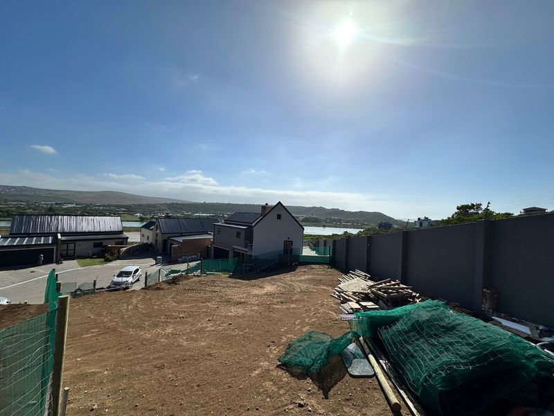 A vacant residential plot featuring a perimeter wall and views of the surrounding neighborhood and landscape.