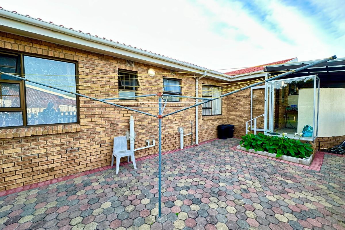A paved rear courtyard featuring a brick facade, external lighting, and a functional rotary clothesline area.