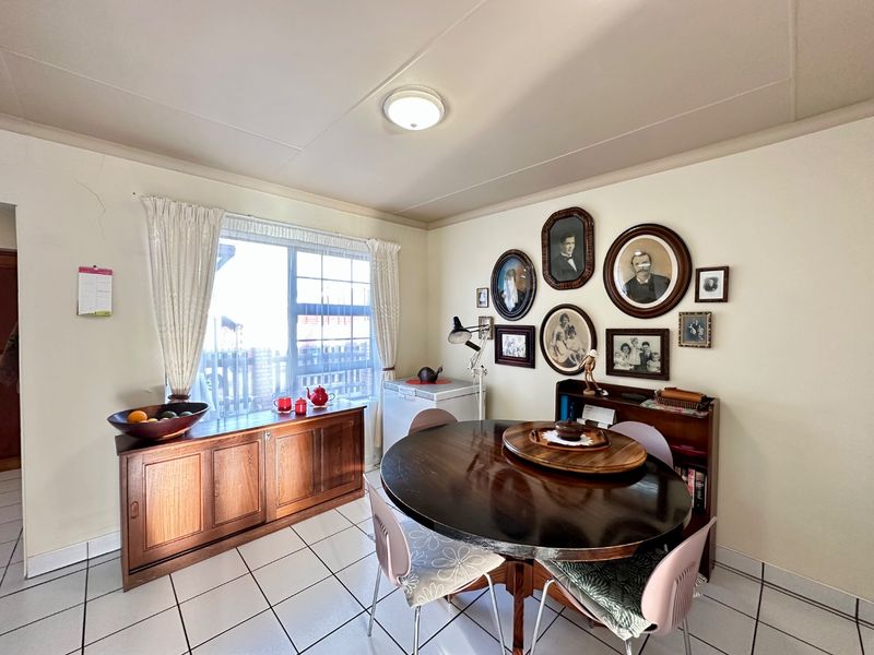 A dining area featuring tiled flooring, a large window providing natural light, and a ceiling-mounted light fixture.