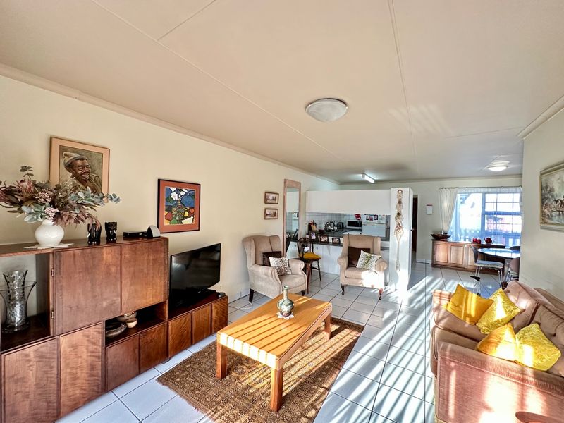 An open-plan living and dining area featuring tiled flooring and a functional kitchen with a breakfast bar, offering a bright and versatile living space.