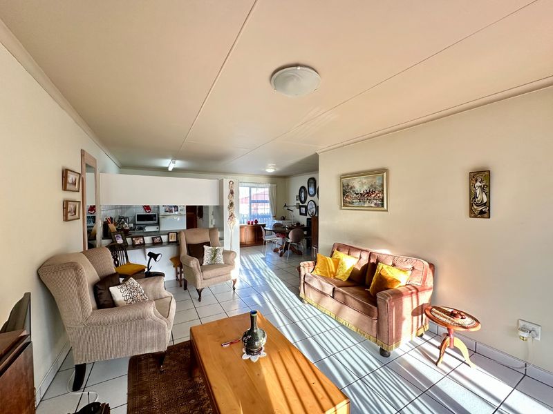 Open plan living and dining area featuring tiled flooring and a breakfast bar connecting to the kitchen space.