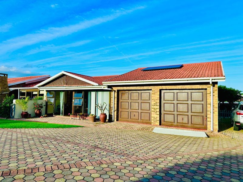 Front exterior view of a townhouse featuring a double garage, tiled roof with solar panels, and paved driveway.