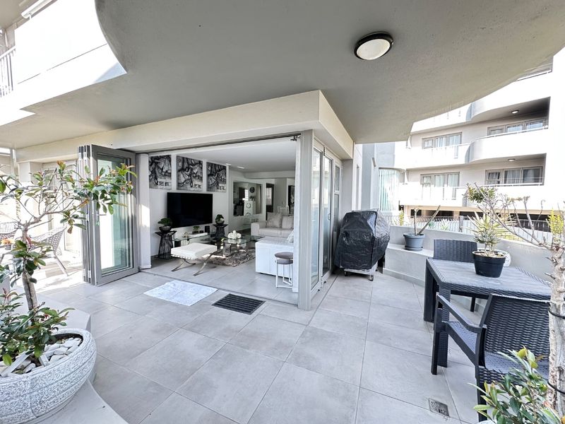 Spacious covered balcony featuring large-format floor tiles and seamless bi-fold door access to the interior living area.