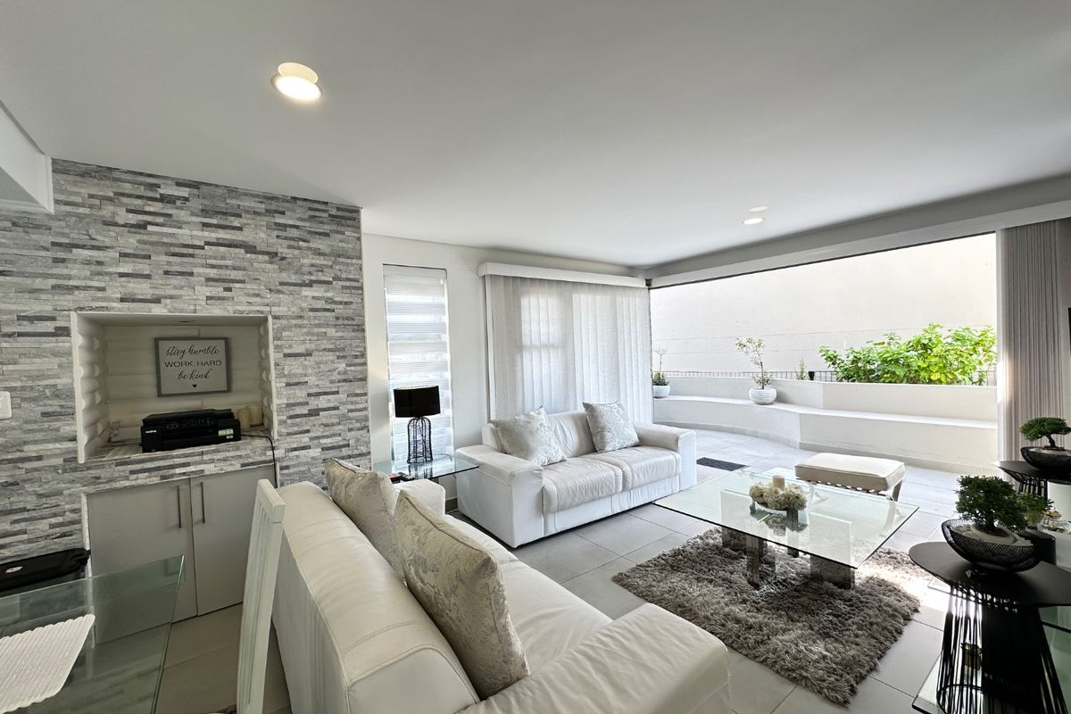 Spacious living room featuring a modern stone feature wall, built-in cabinetry, and large sliding glass doors that open onto a private balcony.