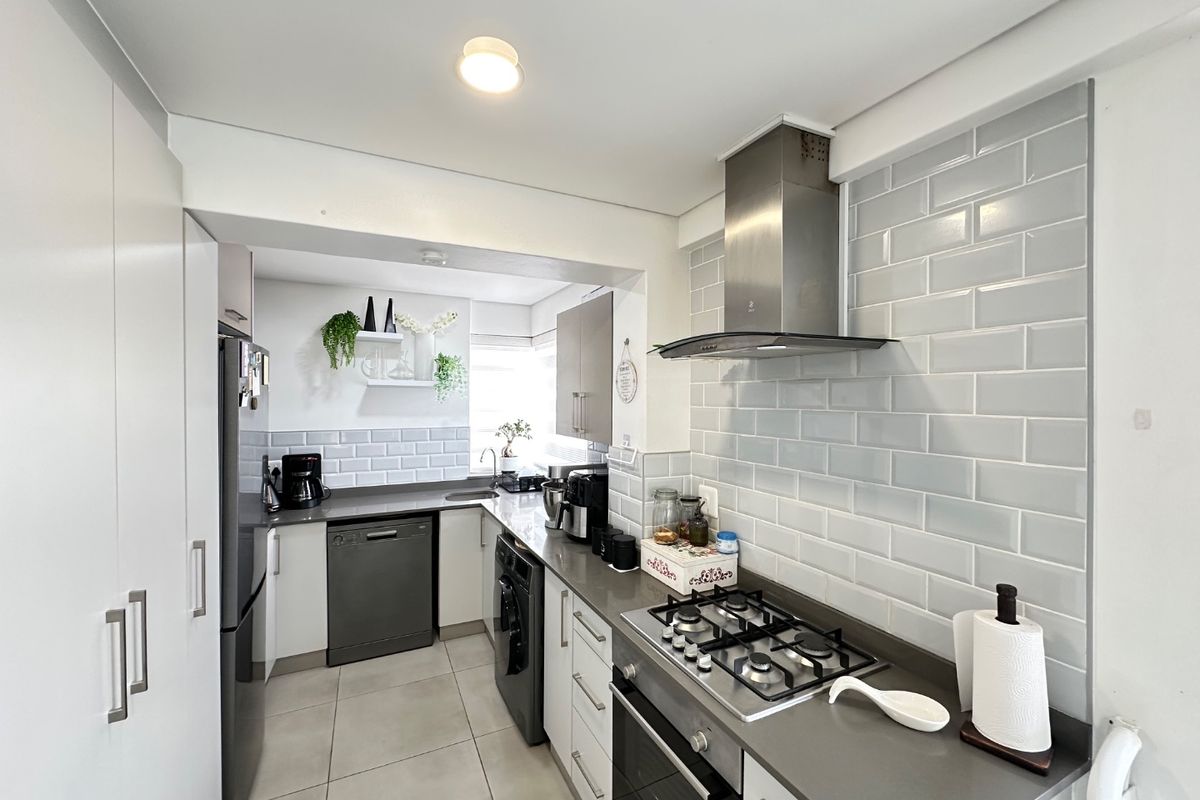 Modern kitchen featuring stone countertops, subway tile backsplash, gas cooktop, built-in oven, stainless steel extractor fan, and ample integrated cabinetry.
