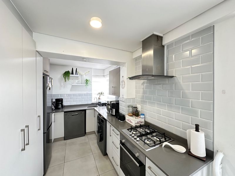 Modern kitchen featuring stone countertops, subway tile backsplash, gas cooktop, built-in oven, stainless steel extractor fan, and ample integrated cabinetry.