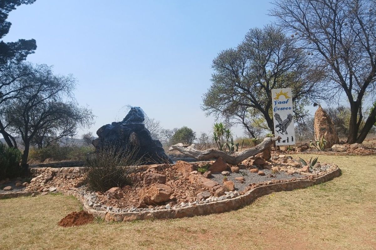 A landscaped garden area featuring a rockery, a water feature, and a decorative sign on a vacant residential property.