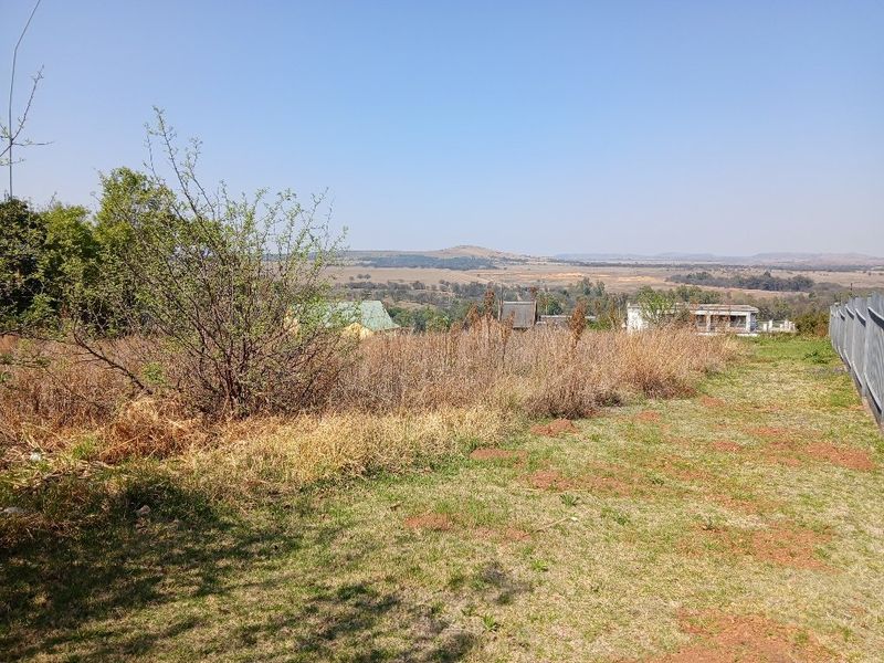 A wide-angle view of the vacant residential land featuring natural vegetation and distant landscape scenery.