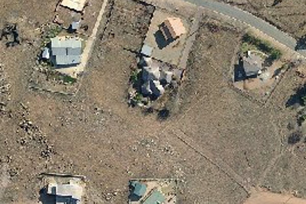 An aerial view of a residential area showing multiple plots of land, existing dwellings, and surrounding road infrastructure.