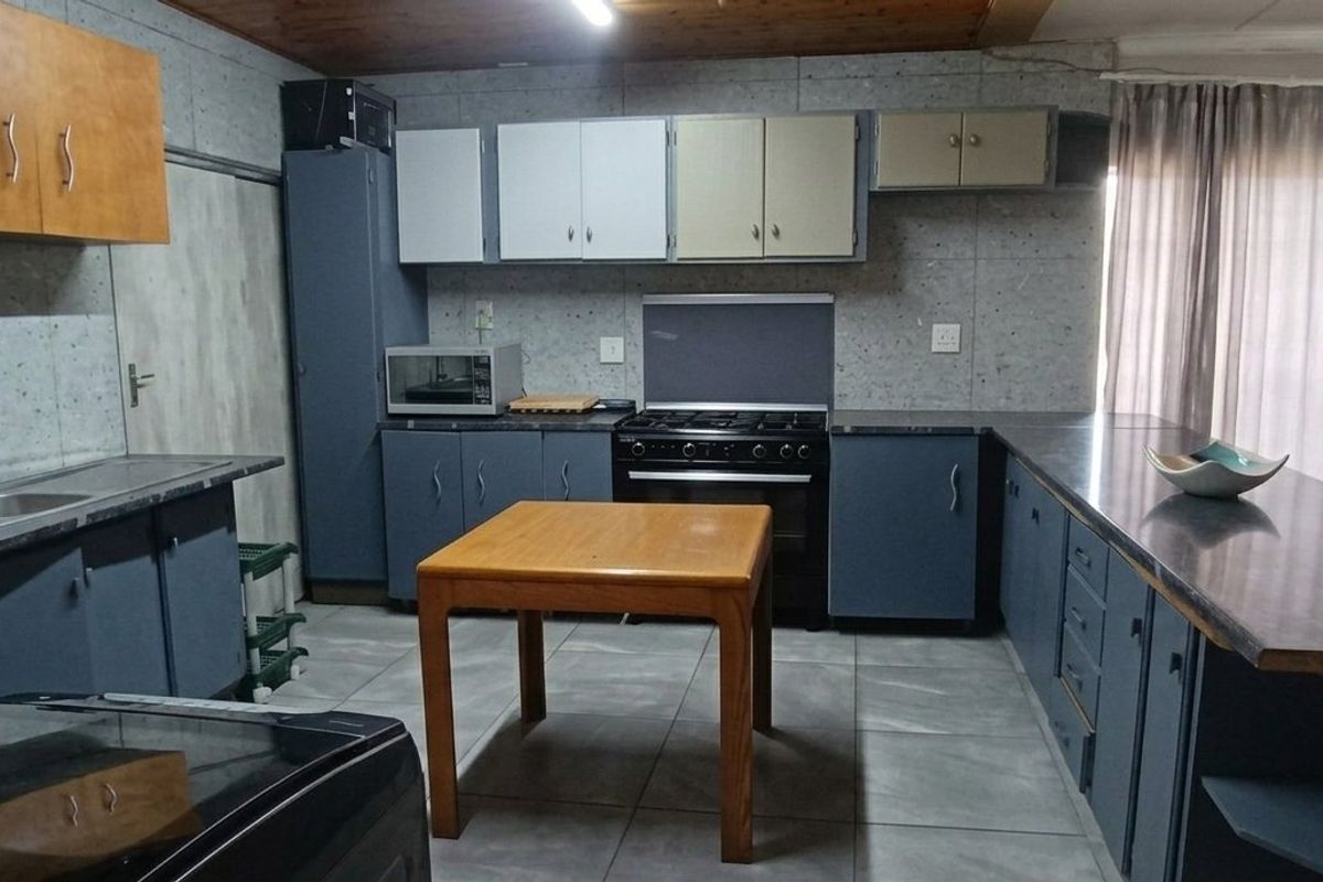 A functional kitchen featuring tiled flooring, built-in cabinetry, a gas stove with oven, and a double bowl sink with laminate countertops.