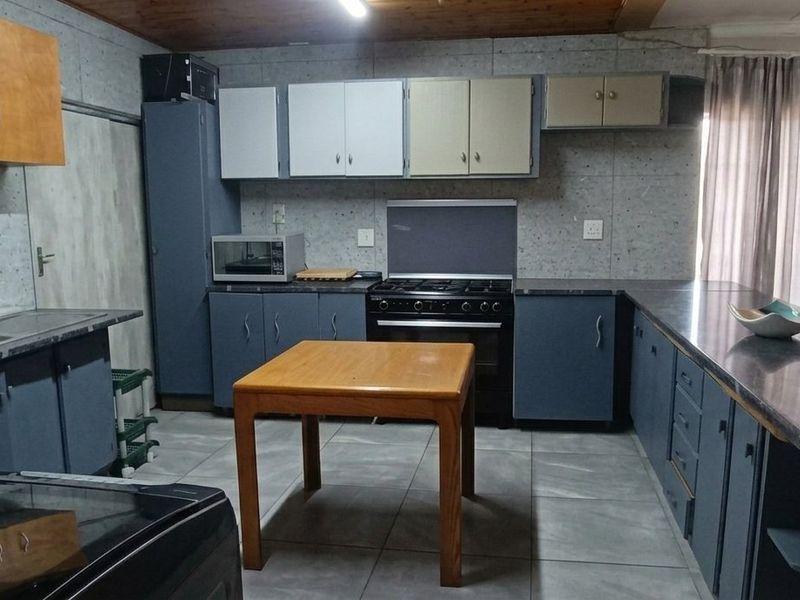 A functional kitchen featuring tiled flooring, built-in cabinetry, a gas stove with oven, and a double bowl sink with laminate countertops.