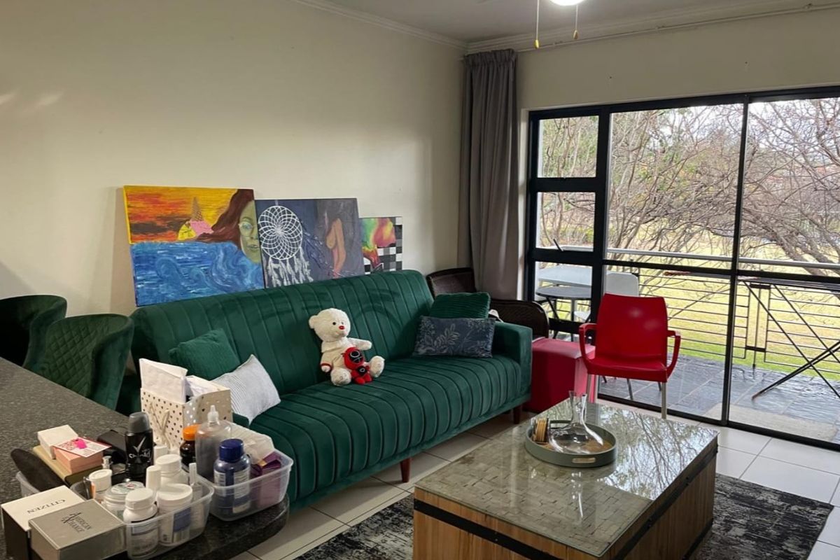 A living room area featuring tiled flooring, a ceiling fan, and large sliding glass doors providing access to an outdoor balcony.