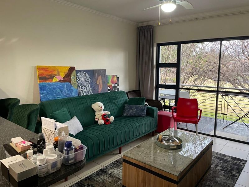 A living room area featuring tiled flooring, a ceiling fan, and large sliding glass doors providing access to an outdoor balcony.