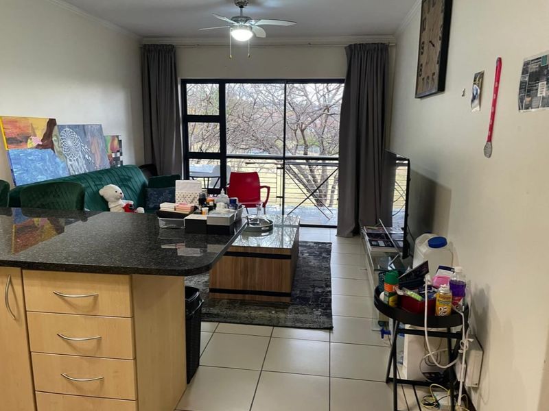Open-plan living area featuring tiled floors, a kitchen island with granite countertops, and a sliding door leading to a balcony.