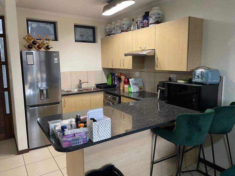 Compact kitchen featuring light wood cabinetry, granite countertops, a breakfast bar, and tiled flooring, providing a functional and efficient cooking space.