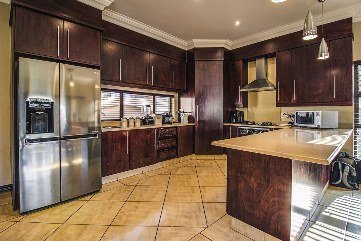 A well-appointed kitchen featuring dark wood cabinetry, stone countertops, stainless steel appliances, and tiled flooring with a functional layout.