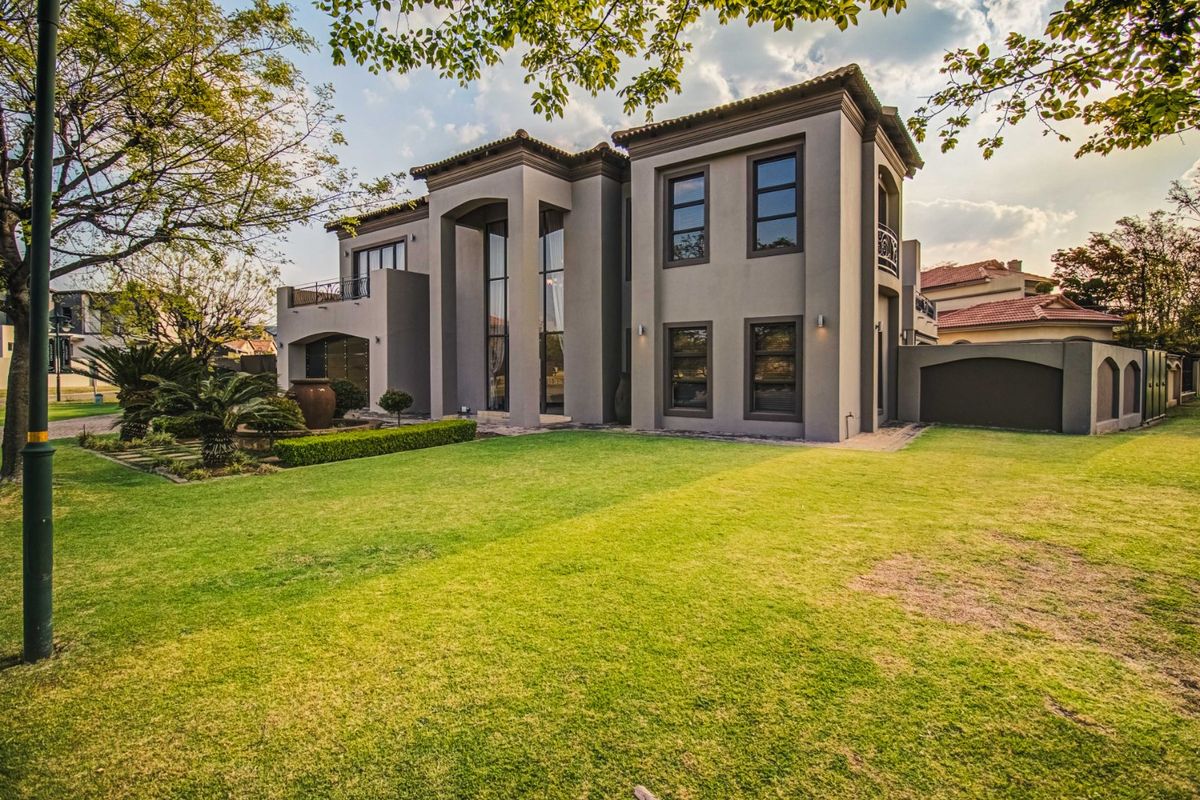 A well-maintained double-story residence featuring a spacious rear garden, paved pathways, and a balcony overlooking the landscaped outdoor area.