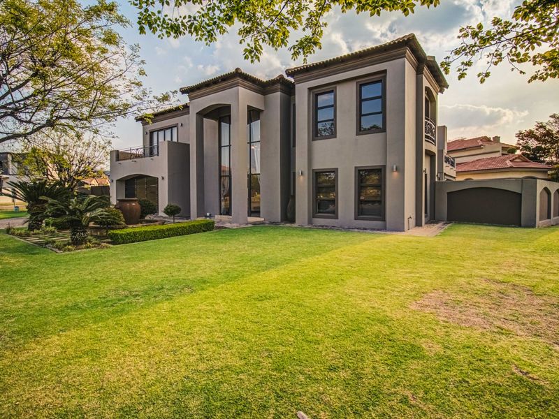 A well-maintained double-story residence featuring a spacious rear garden, paved pathways, and a balcony overlooking the landscaped outdoor area.