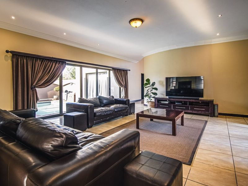 Spacious living room featuring tiled flooring, recessed lighting, and large sliding glass doors providing direct access to the outdoor pool area.