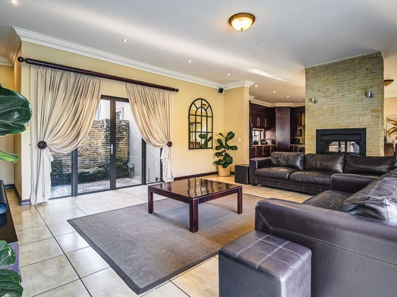 Spacious open-plan living area featuring a stone-clad fireplace, tiled flooring, and sliding glass doors leading to a private outdoor courtyard.