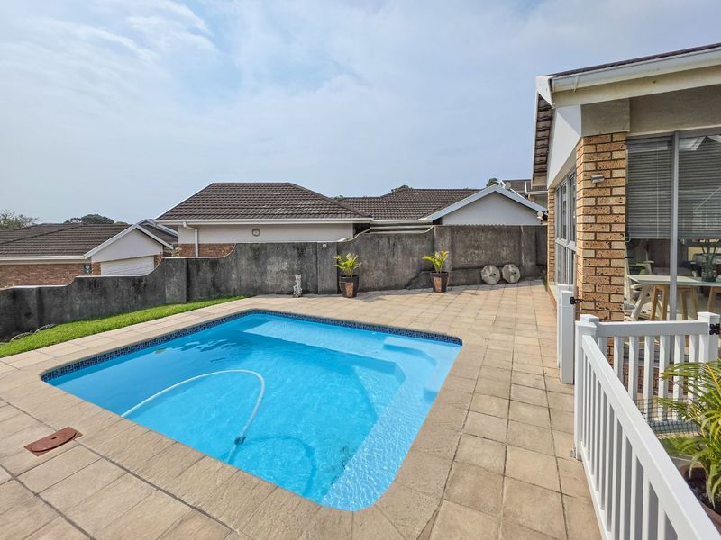 A private outdoor pool area featuring a paved patio, brick boundary wall, and direct access to the townhouse living space.