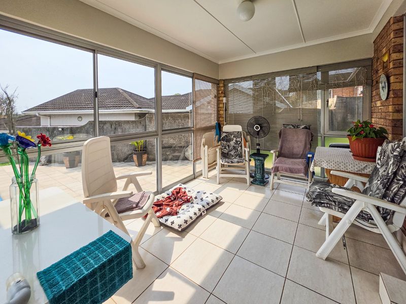 Enclosed patio area featuring tiled flooring, large sliding glass doors, and an exposed brick feature wall, offering a bright and versatile living space.