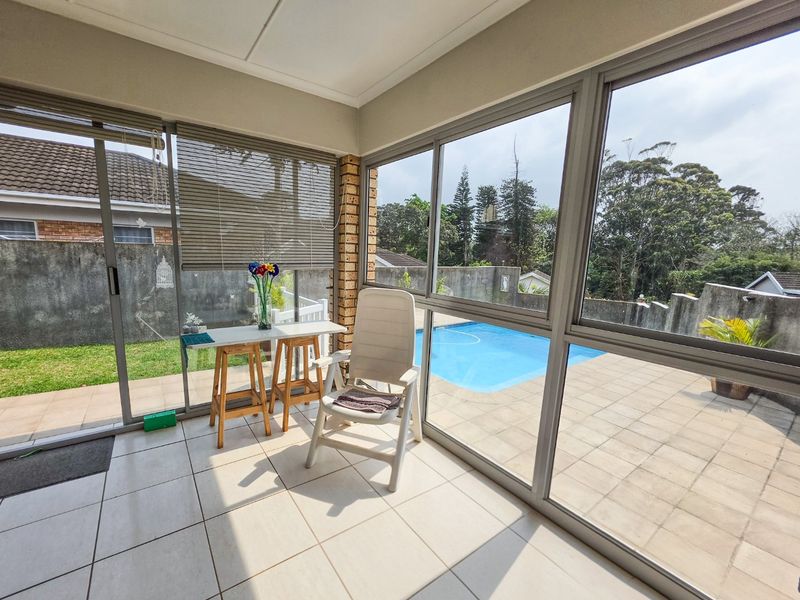 Enclosed patio area featuring tiled flooring and large sliding glass doors, offering direct views of the swimming pool and garden.