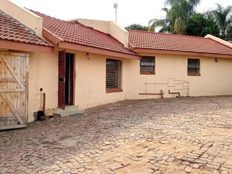 Rear exterior view of the property featuring terracotta roof tiles, cobblestone paving, and security features on windows and doors.