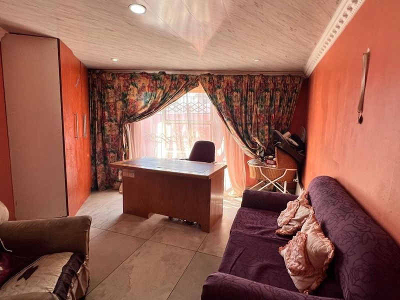 A bedroom featuring built-in cupboards, tiled flooring, and recessed lighting, currently utilized as a home office space.