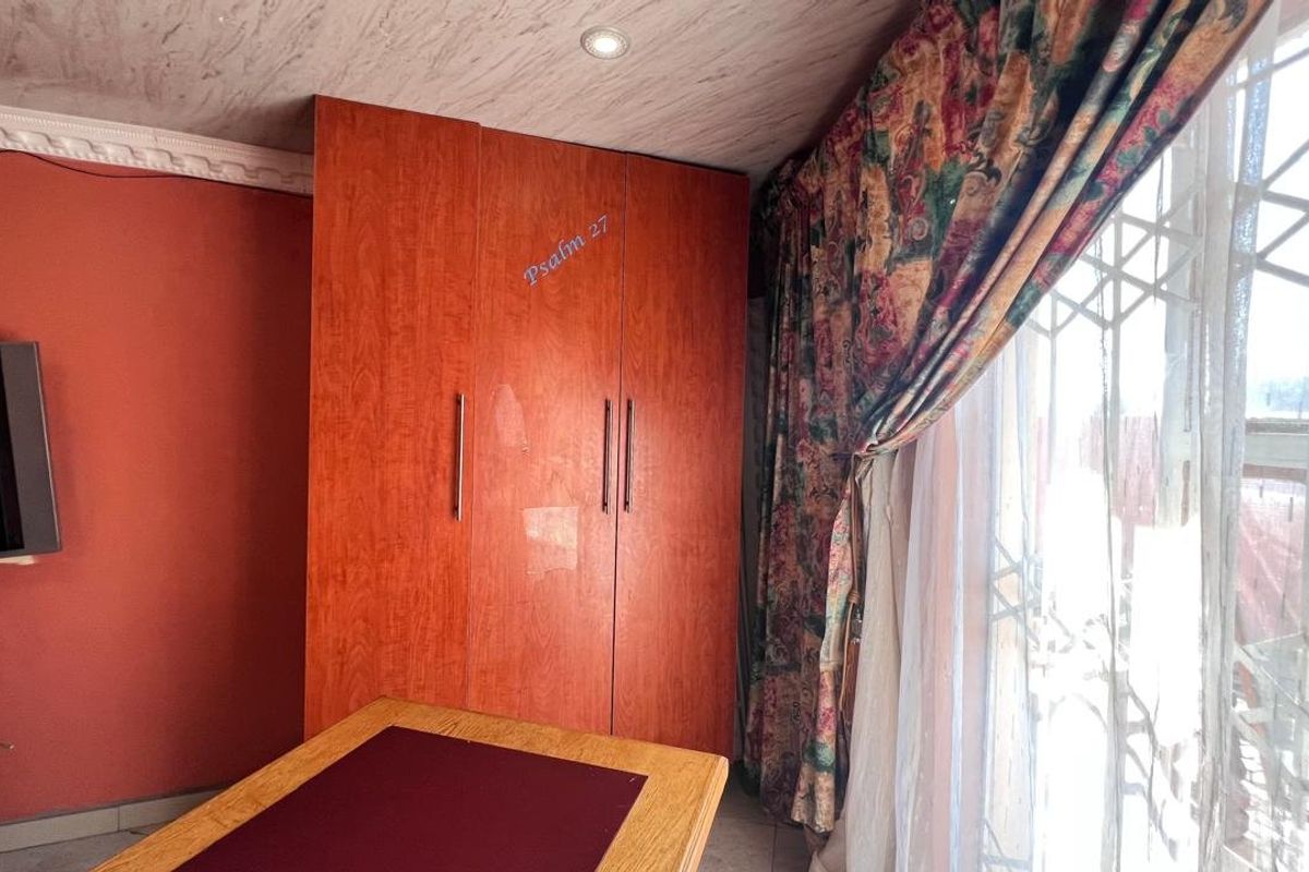 Bedroom featuring built-in wooden cupboards, recessed ceiling lighting, and a security gate over the window.