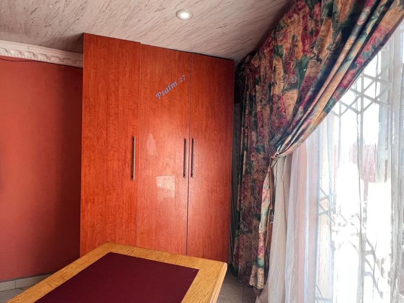 Bedroom featuring built-in wooden cupboards, recessed ceiling lighting, and a security gate over the window.