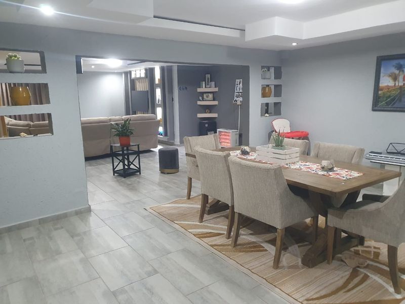 An open-plan living and dining area featuring modern tiled flooring, recessed ceiling lighting, and decorative built-in wall niches.