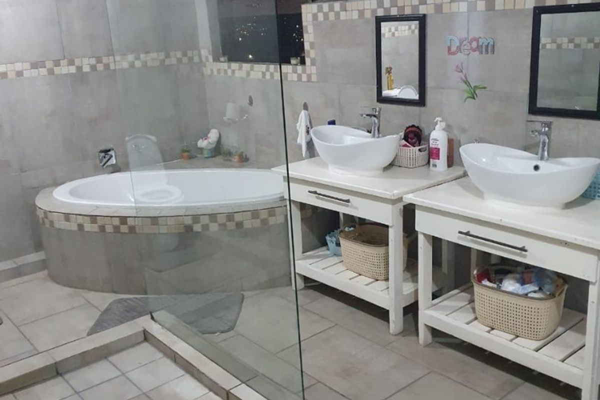 Spacious bathroom featuring a built-in bathtub, glass-enclosed shower, and a double vanity with vessel sinks and tiled finishes.