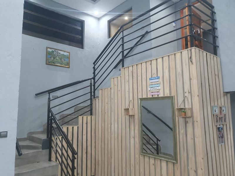 A bright hallway featuring a modern staircase with black metal railings and decorative timber wall cladding.