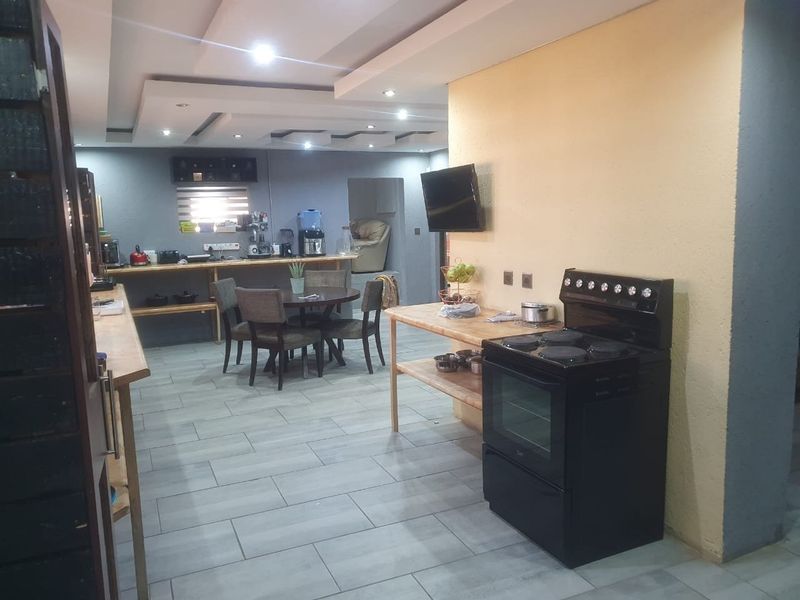 Open-plan kitchen and dining area featuring tiled flooring, recessed ceiling lighting, and a freestanding electric stove.