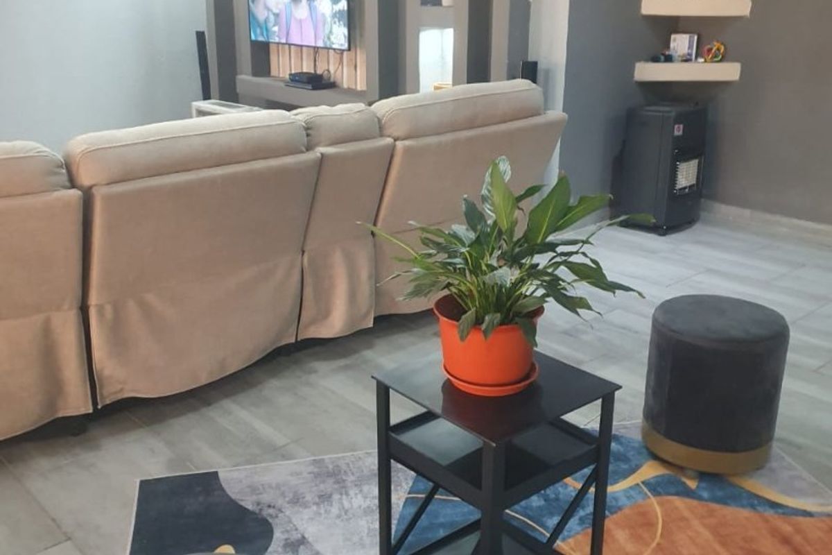 A modern living room featuring a built-in media wall with recessed shelving, integrated lighting, and neutral tiled flooring.
