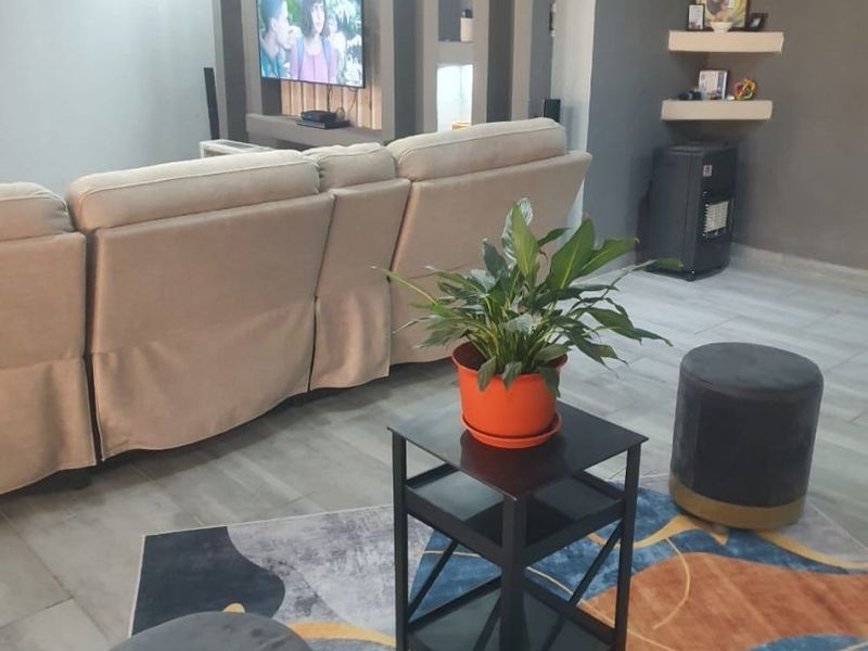 A modern living room featuring a built-in media wall with recessed shelving, integrated lighting, and neutral tiled flooring.