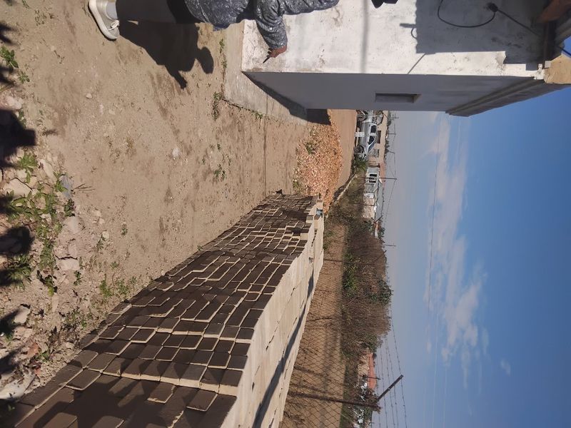 A view of the rear exterior area showing a chain link fence, unfinished wall structure, and unpaved ground.