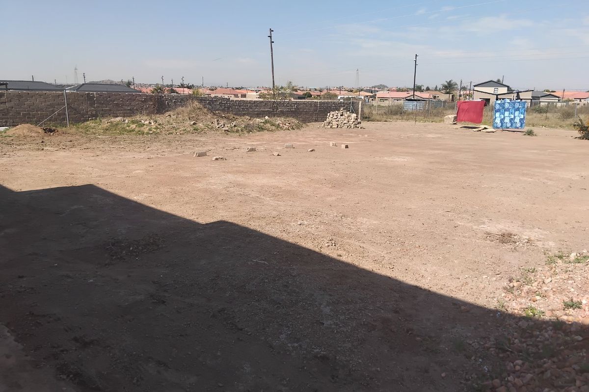 A large, undeveloped rear yard area featuring a perimeter wall and open ground, offering significant potential for landscaping or future outdoor development.