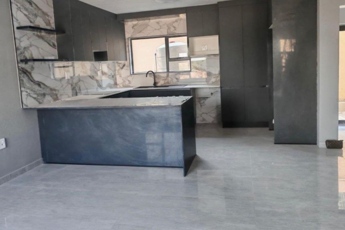 Modern kitchen featuring dark cabinetry, marble-look splashbacks, a central island, and sleek tiled flooring in an open-plan layout.