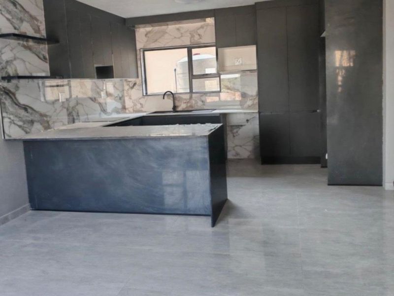 Modern kitchen featuring dark cabinetry, marble-look splashbacks, a central island, and sleek tiled flooring in an open-plan layout.