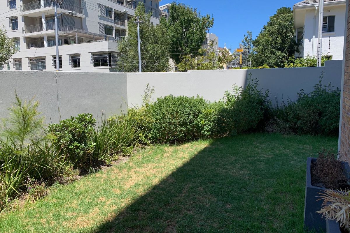 A private rear garden area featuring a well-maintained lawn and a solid boundary wall, providing a secure outdoor space.