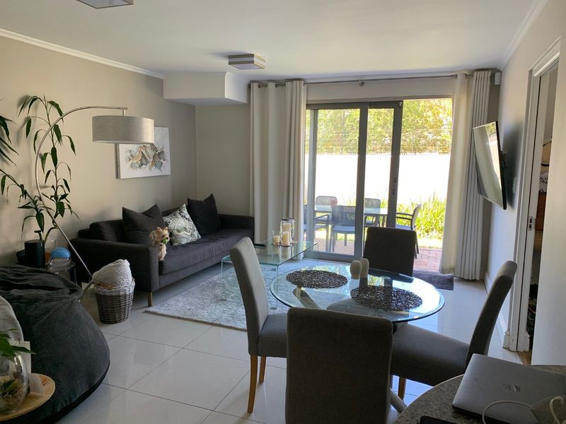 Bright open-plan living and dining area featuring large format floor tiles and sliding glass doors providing direct access to the outdoor patio space.