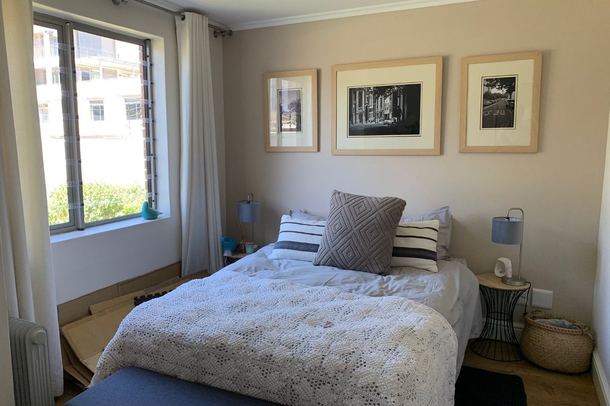 A well-maintained bedroom featuring laminate flooring, neutral wall tones, and a large window providing natural light.