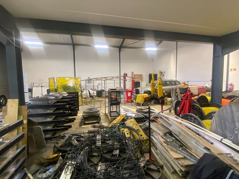 Spacious industrial utility area featuring exposed steel structural beams, high ceilings, and concrete flooring, suitable for workshop or storage operations.
