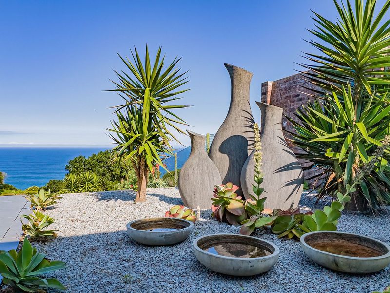 A landscaped garden area featuring gravel ground cover, decorative stone elements, and a scenic ocean view in the background.
