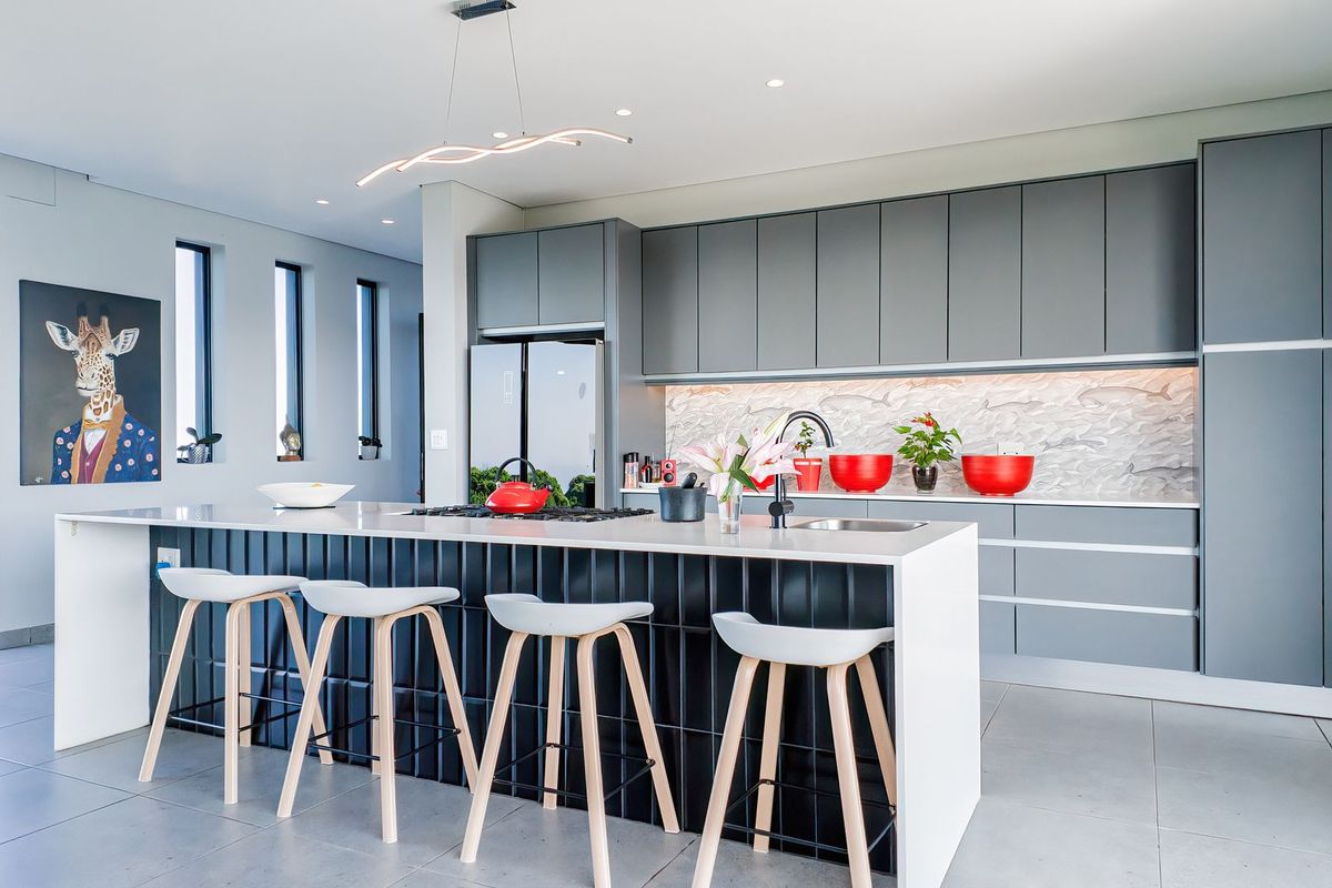 Modern kitchen featuring a large island with stone countertop, sleek grey cabinetry, integrated appliances, and high-quality finishes throughout.