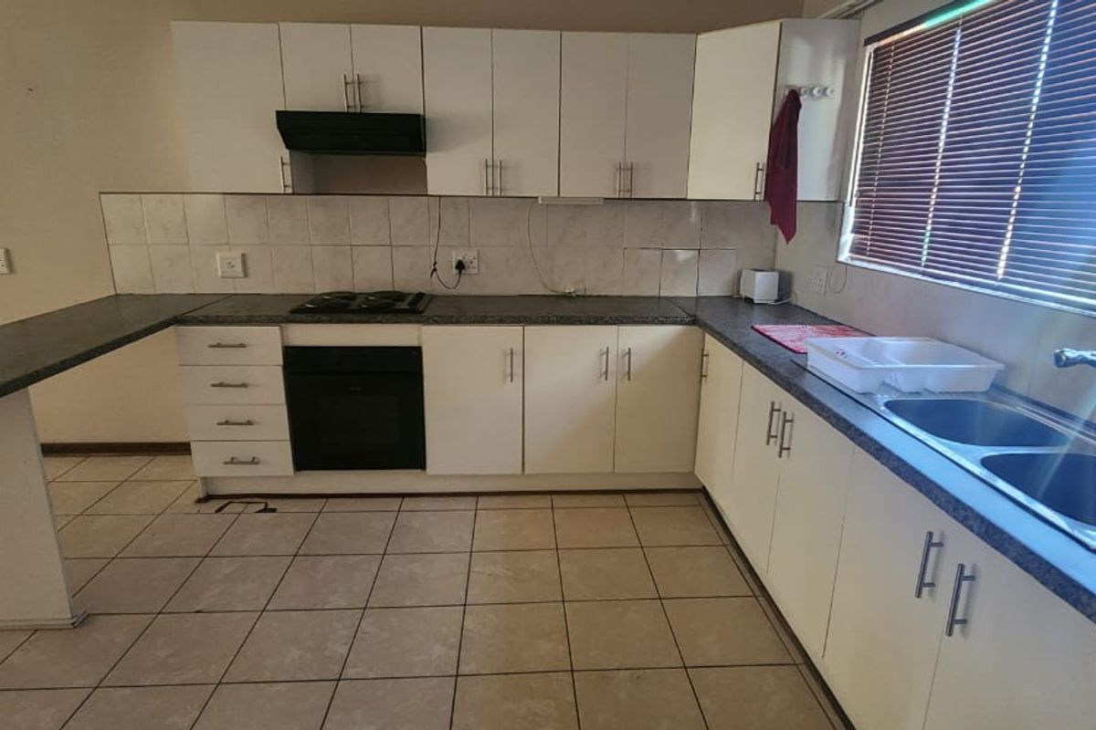 Functional kitchen featuring white cabinetry, dark laminate countertops, built-in oven, gas hob, and a double bowl sink with tiled flooring and backsplash.